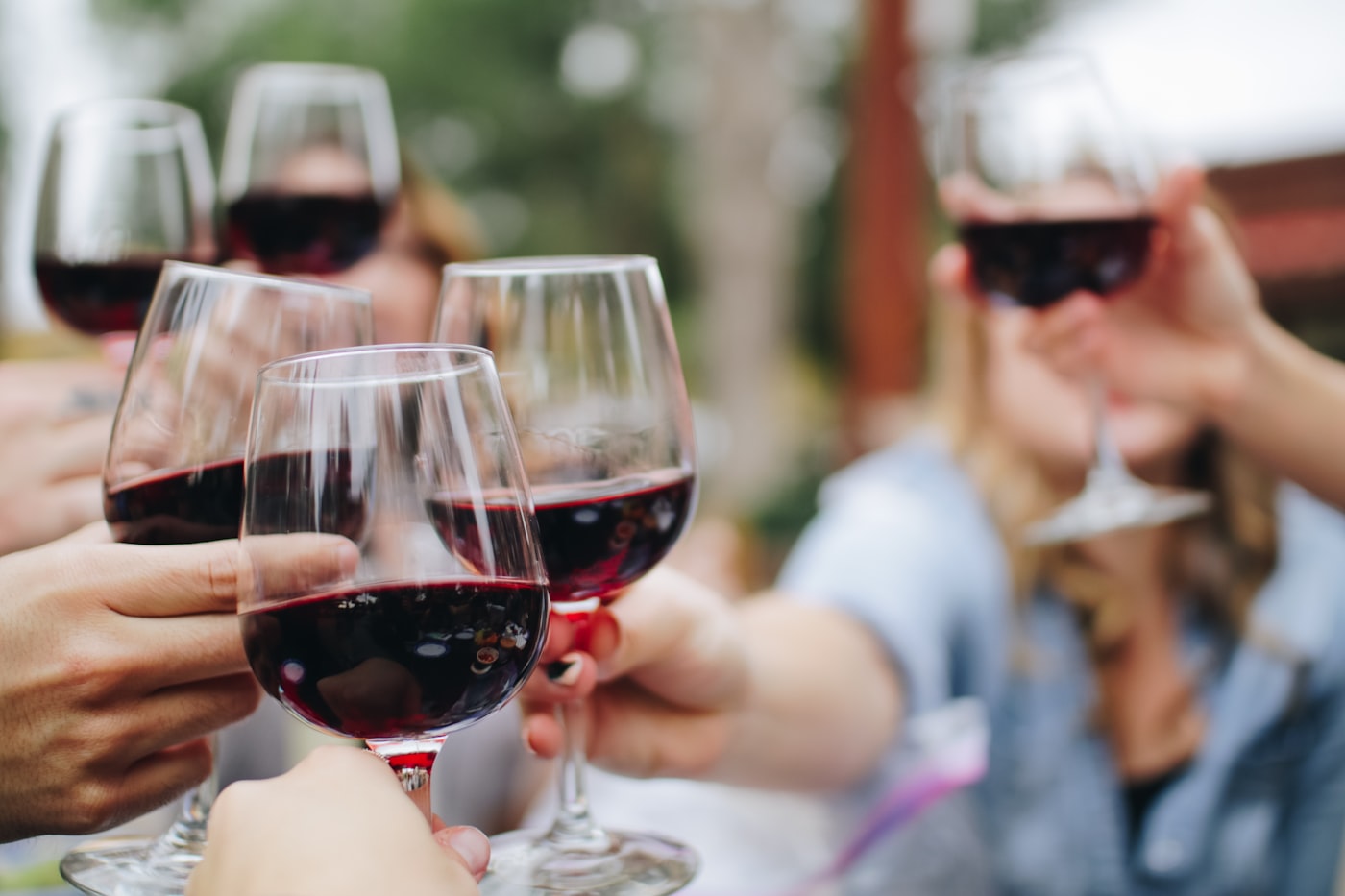 Glasses of red wine raised in a toast outdoors